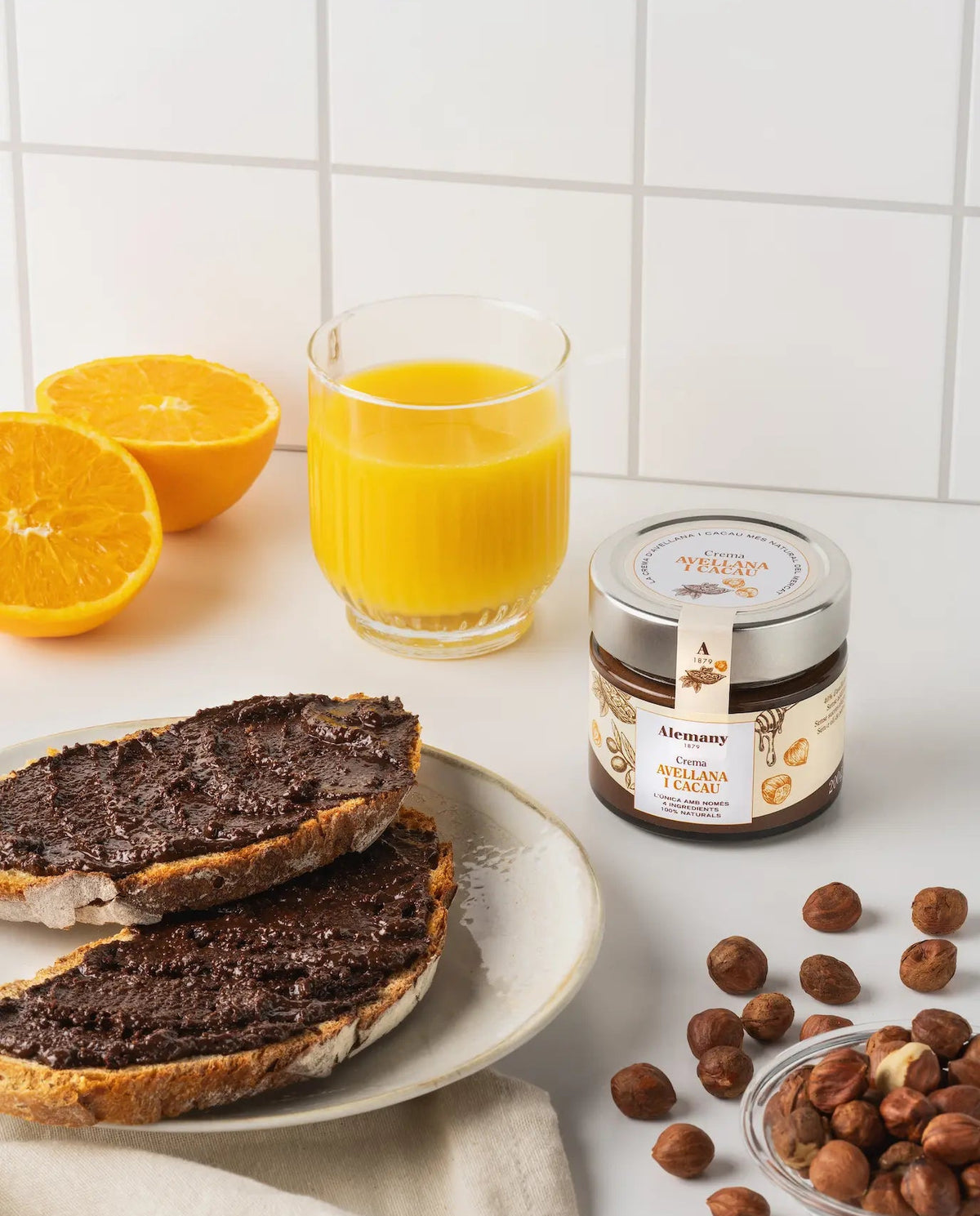 Tostadas con crema de avellana y cacao Alemany junto a zumo y avellanas